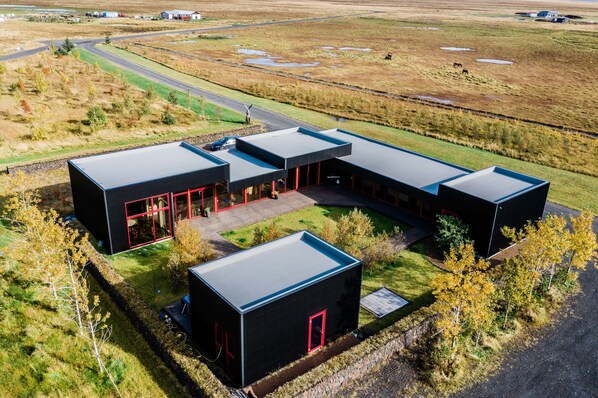 A modern building with a flat roof, a central courtyard, and a surrounding landscape.