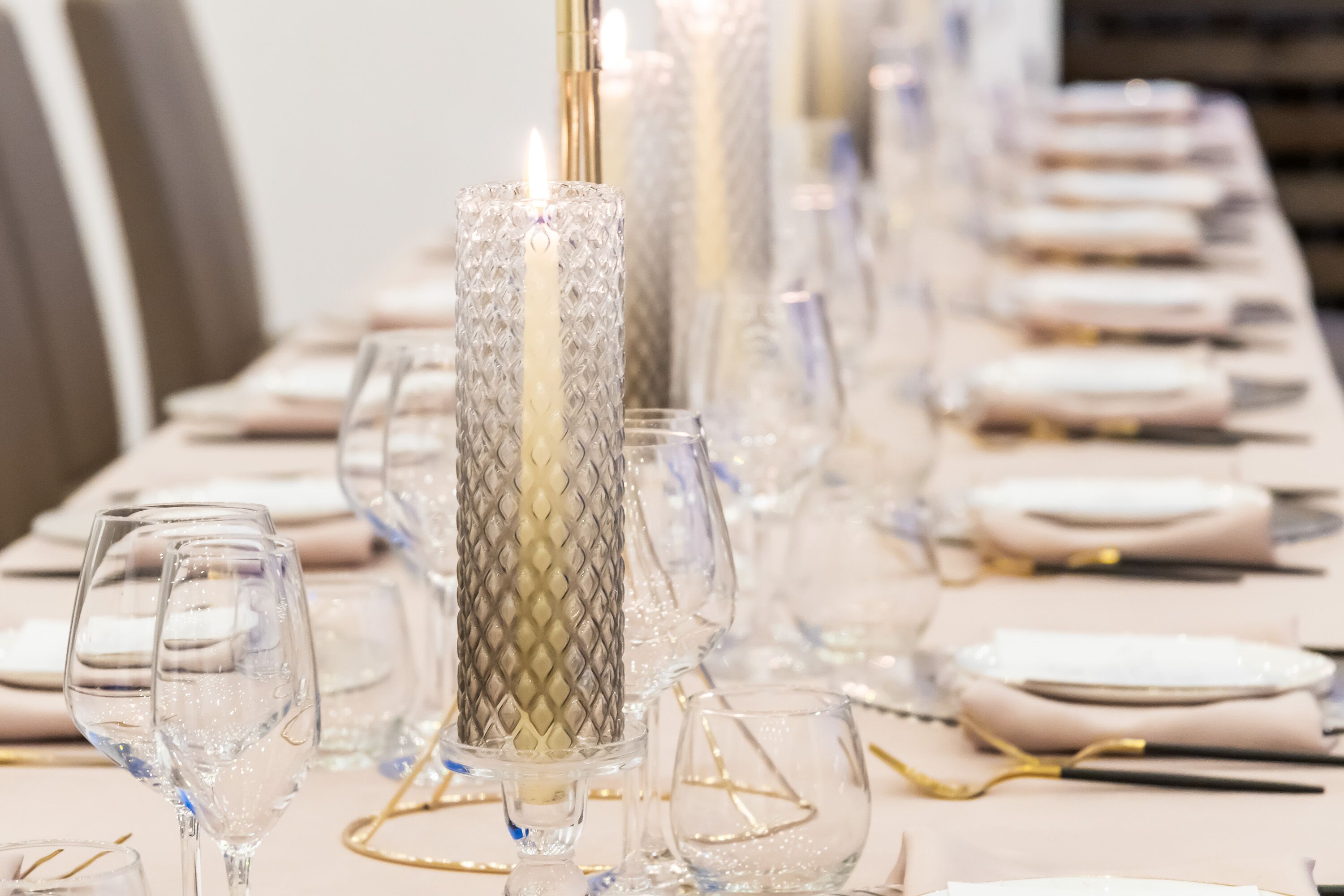 A table set with clear glassware, white plates, and gold cutlery.