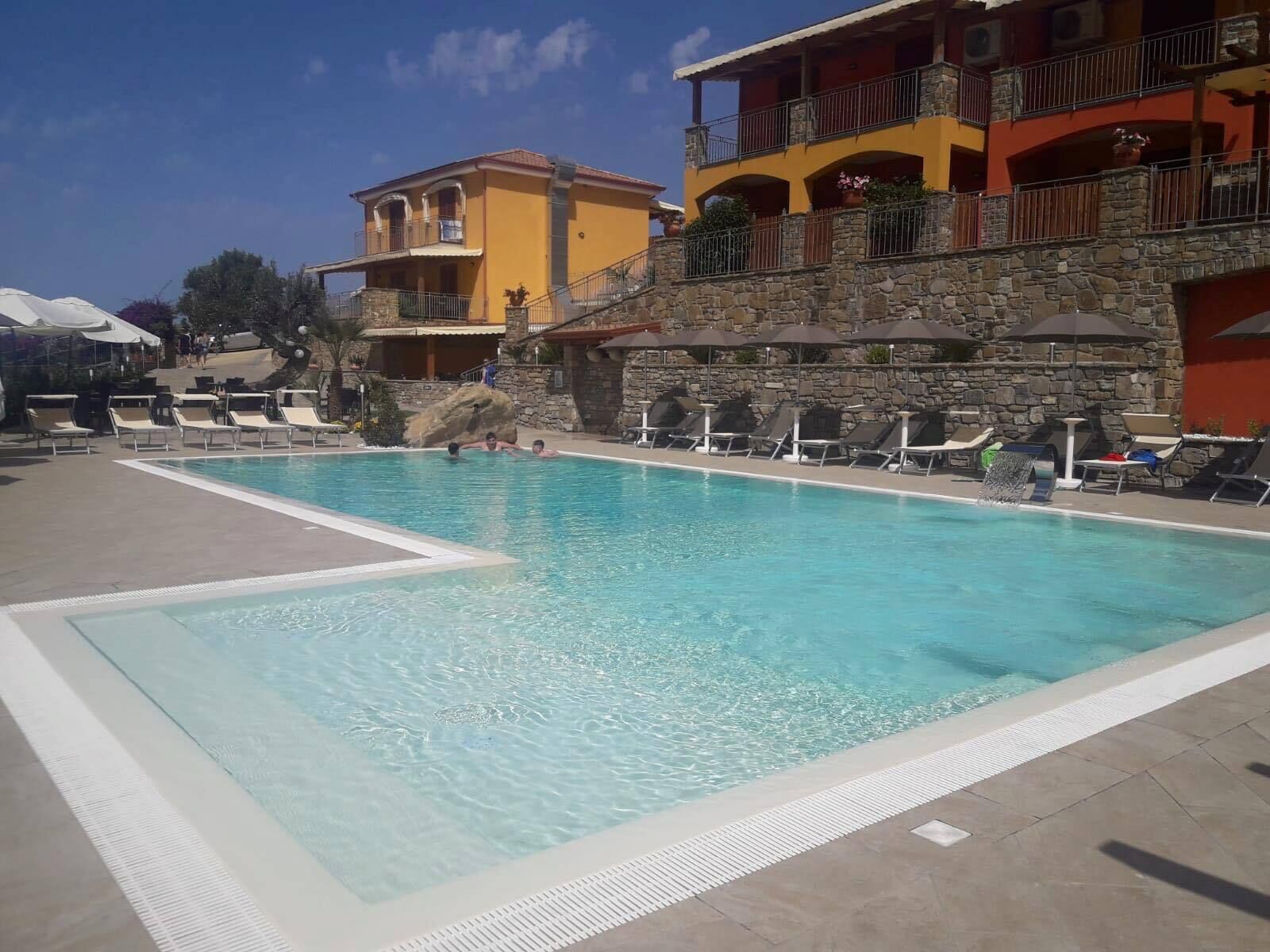 A swimming pool with lounge chairs and a stone wall.
