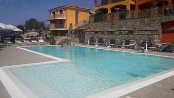 A swimming pool with lounge chairs and a stone wall.