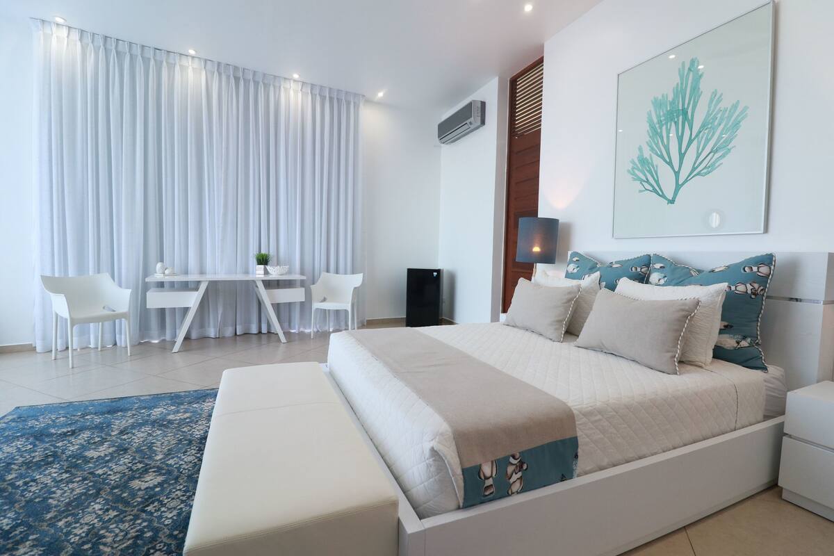 A modern bedroom with a large bed, a desk, and a chair.