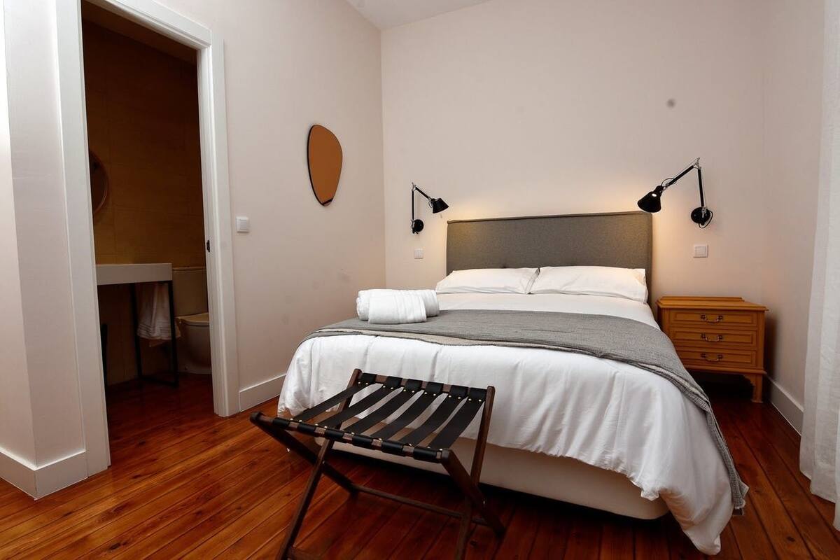 Een slaapkamer met een bed, nachtkastjes, een handdoekhouder en een houten vloer.