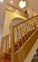 Una escalera de madera con barandilla que lleva a un piso superior.