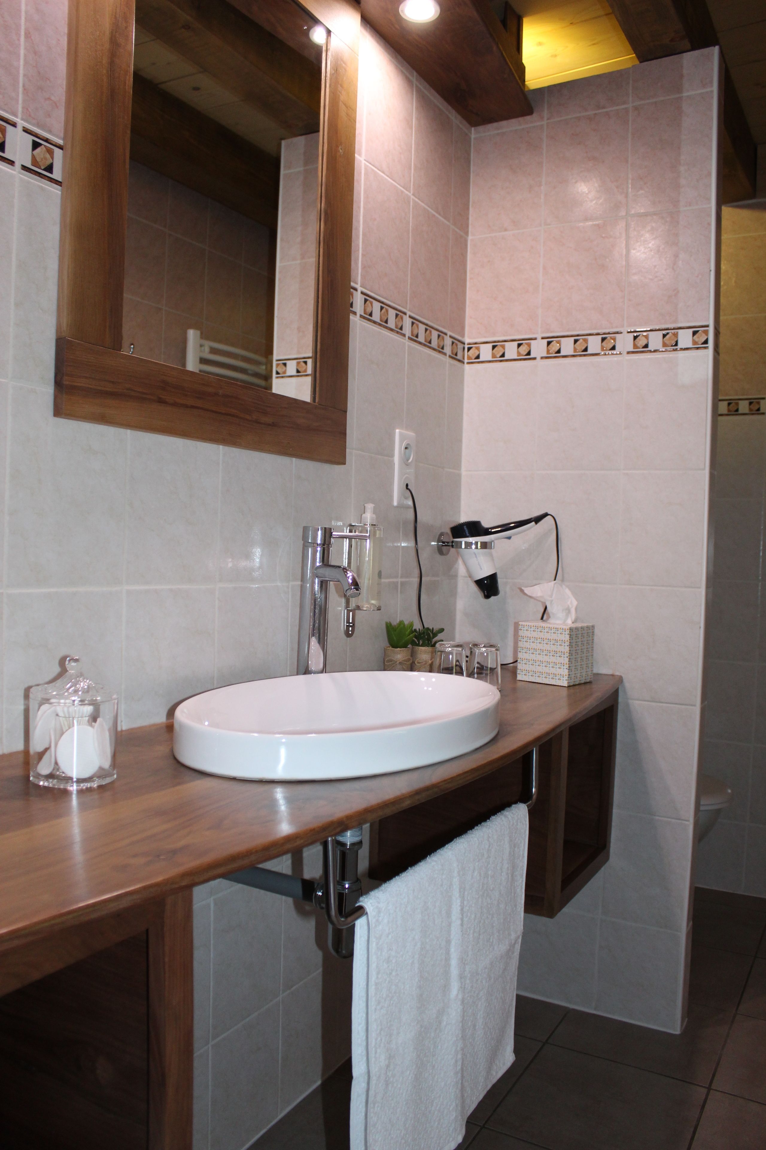 A bathroom with a wooden vanity, a white sink, a mirror, and a towel rack.