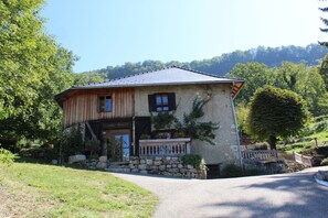 A rustic two-story house with a stone foundation, wooden exterior, and a metal roof. - Les Pipistrelles (Saint-Beron)