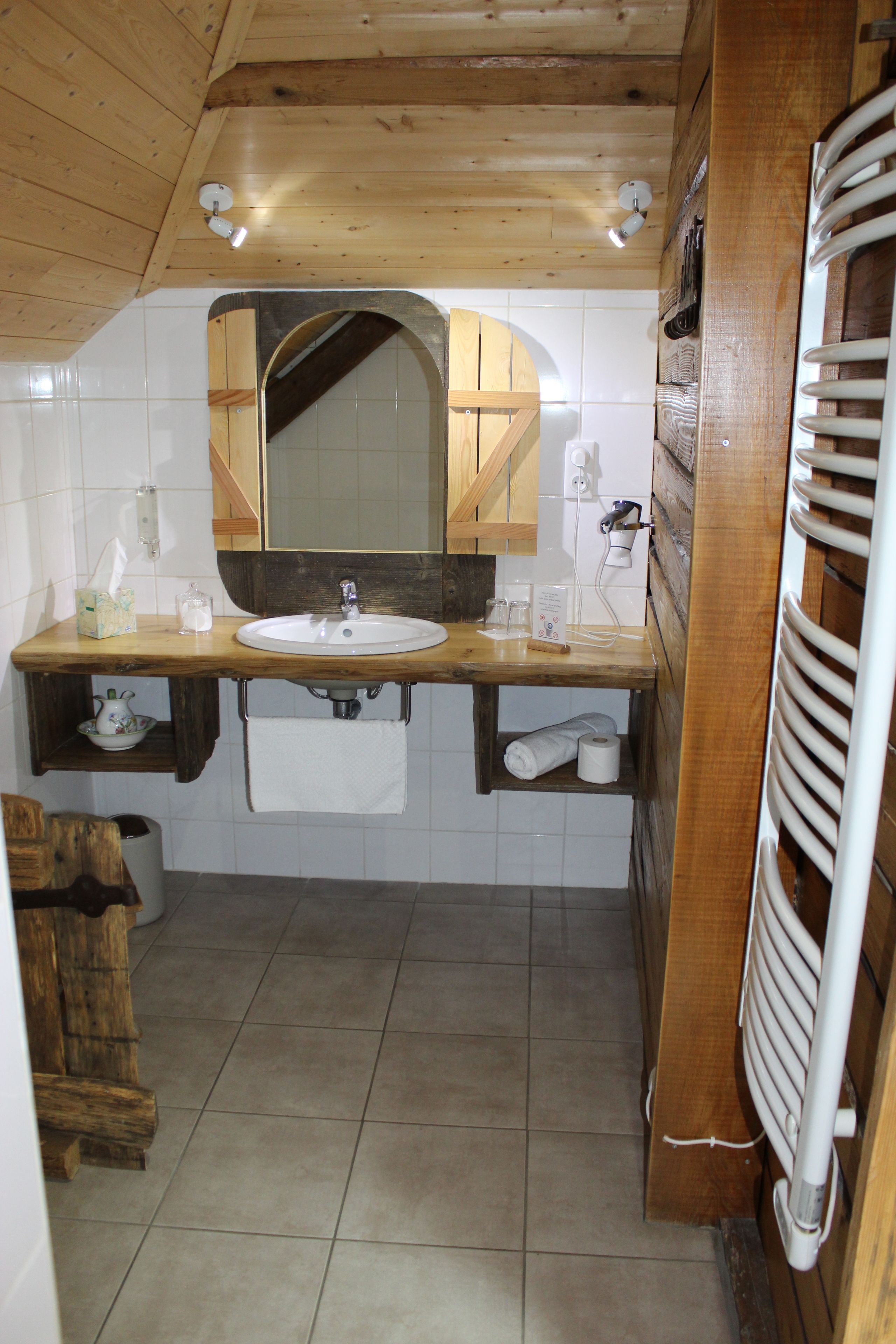 A bathroom with a wooden vanity, a sink, a mirror, and a towel rack.