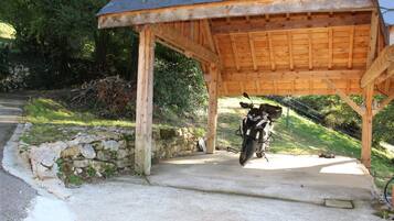 A covered wooden structure with a motorcycle parked underneath.