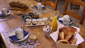 Desayuno con pan, pasteles y bebidas sobre una mesa de madera.
