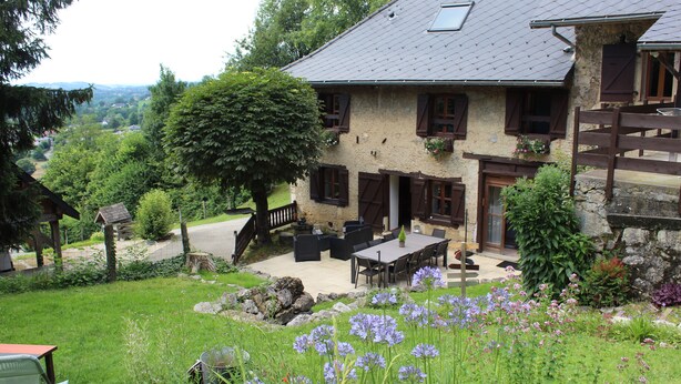 Una casa de piedra con un patio, mobiliario exterior y vistas del paisaje circundante.