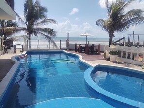 A swimming pool with a view of the ocean, surrounded by palm trees and outdoor furniture. - Hotel Portal Do Mar (Conde)