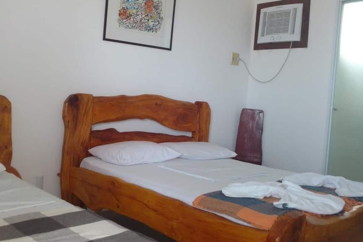 A room with two wooden beds, a checkered rug, and a framed picture on the wall.
