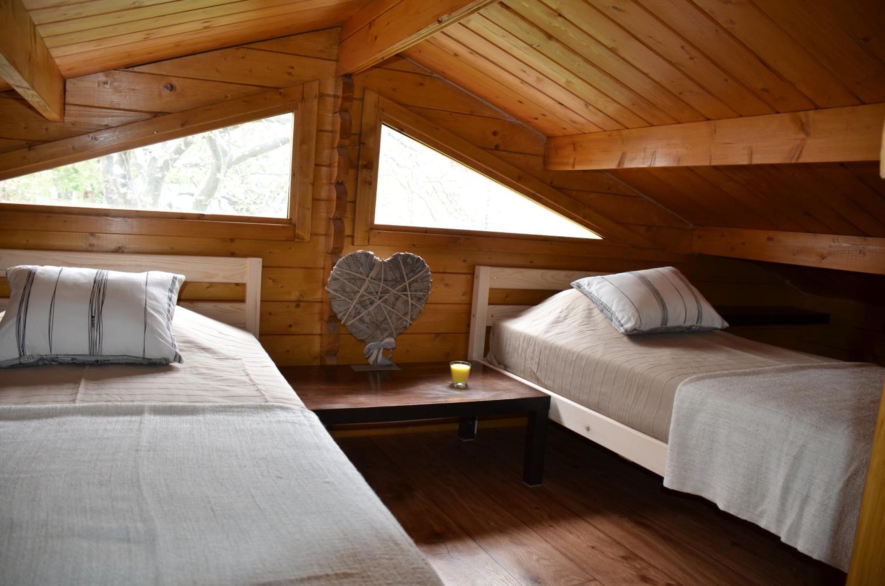 A cabin with two beds, a heart-shaped decoration, and a small table with a glass of juice.