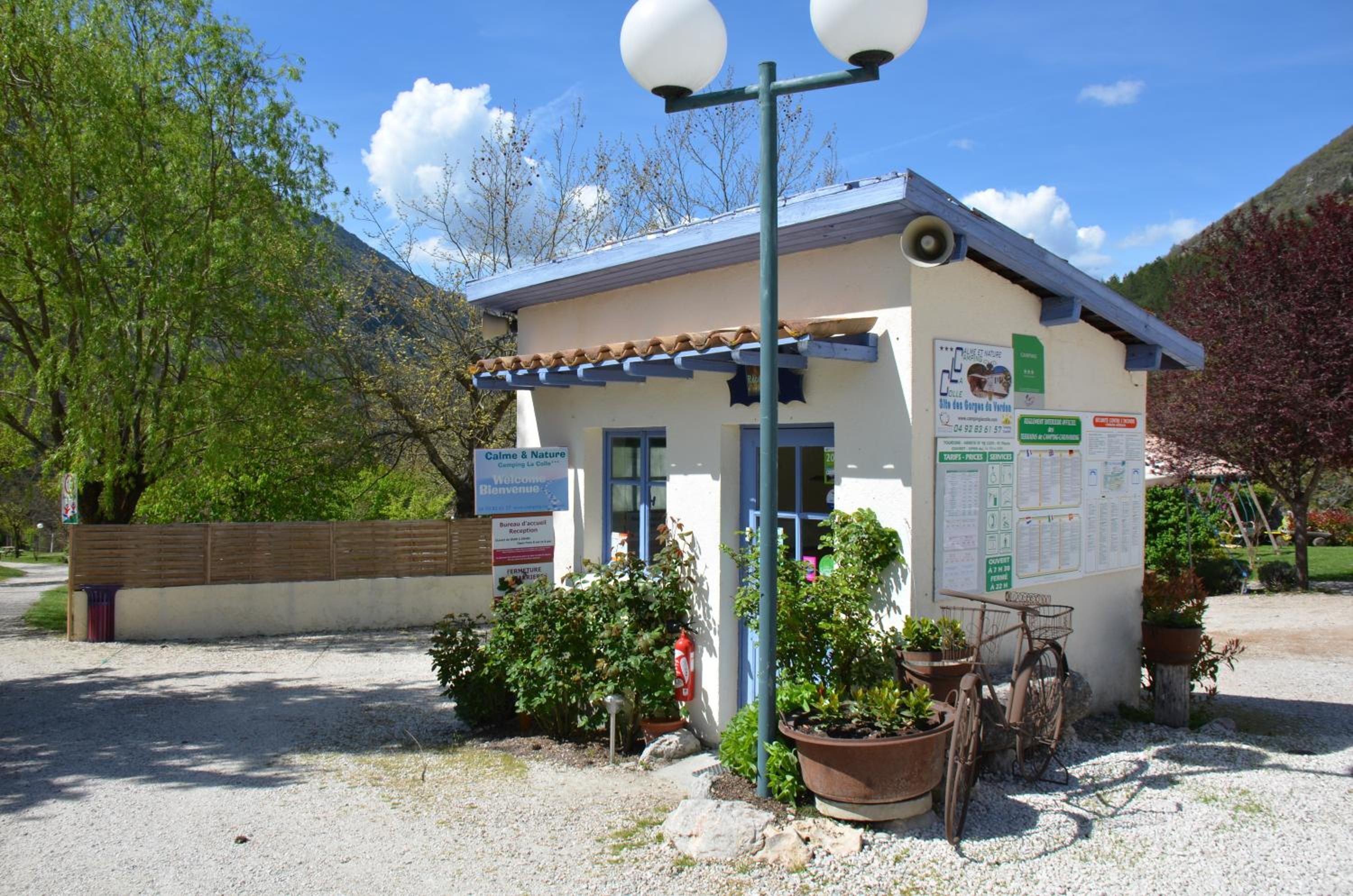 A small building with a signboard, a reception desk, and a bicycle parked outside.