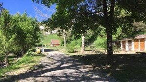 A gravel path leading to a rustic building with a tiled roof, surrounded by greenery and trees. - Calme et Nature (Saint Sever)