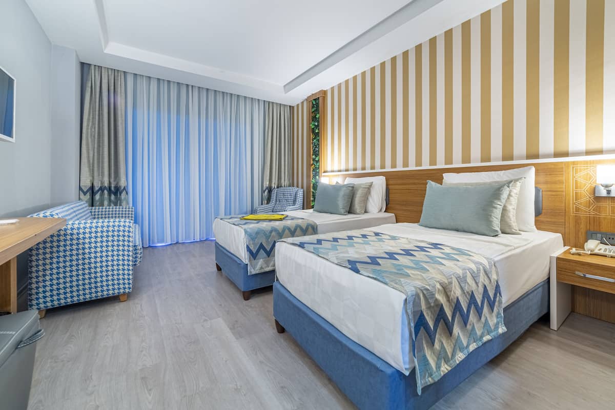 A hotel room with two beds, a desk, and a chair.