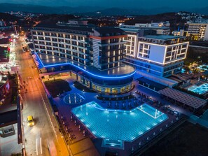 A modern hotel with a central courtyard, multiple floors, and a swimming pool. - Lonicera Premium (Alanya)