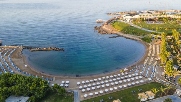 An aerial view of a coastal resort with a beach, lounge areas, and a marina. - Lonicera Premium (Alanya)