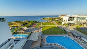 A hotel with a large outdoor pool, a tennis court, and a view of the sea. - Lonicera Premium (Alanya)