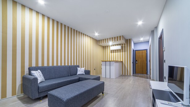 Una sala de estar moderna con un sofá seccional gris, un televisor de pantalla plana y un mueble de madera.