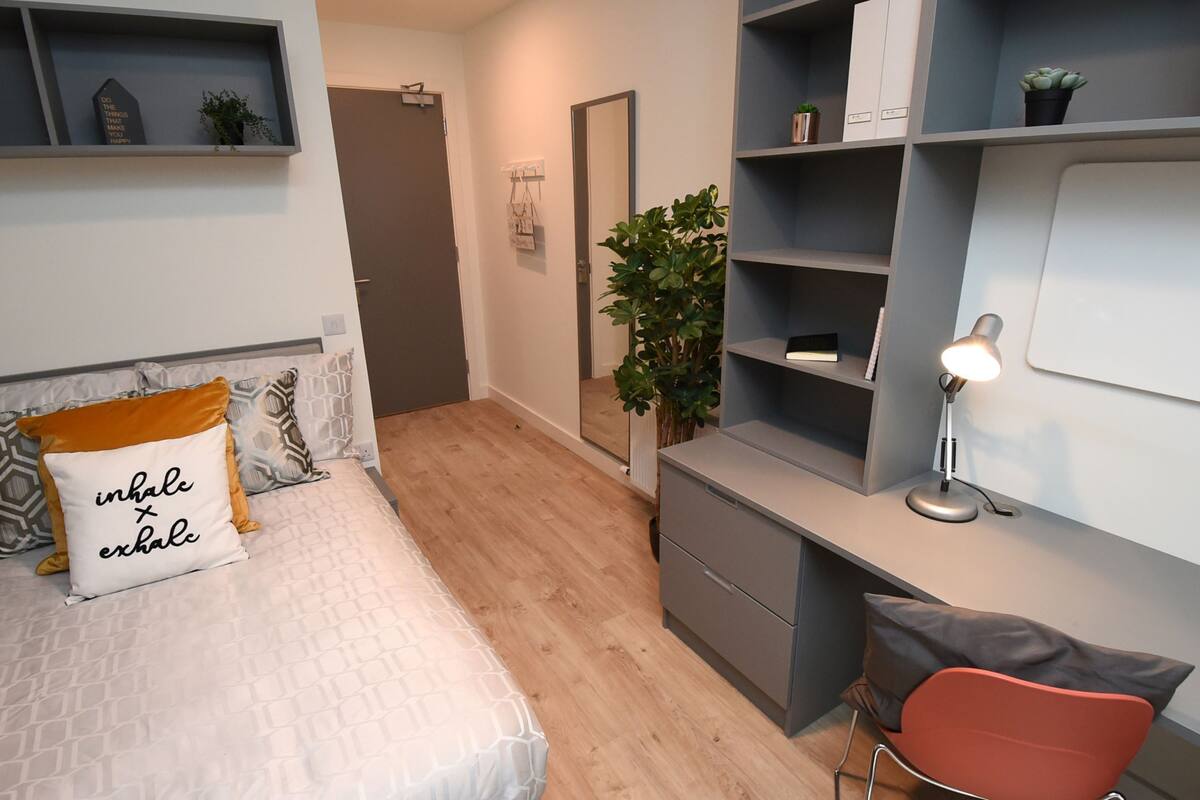 Une chambre moderne avec un lit, une table de chevet et un coin bureau avec une lampe.
