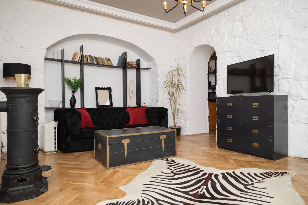 A cozy living room with a fireplace, a sofa, a television, and a patterned rug.