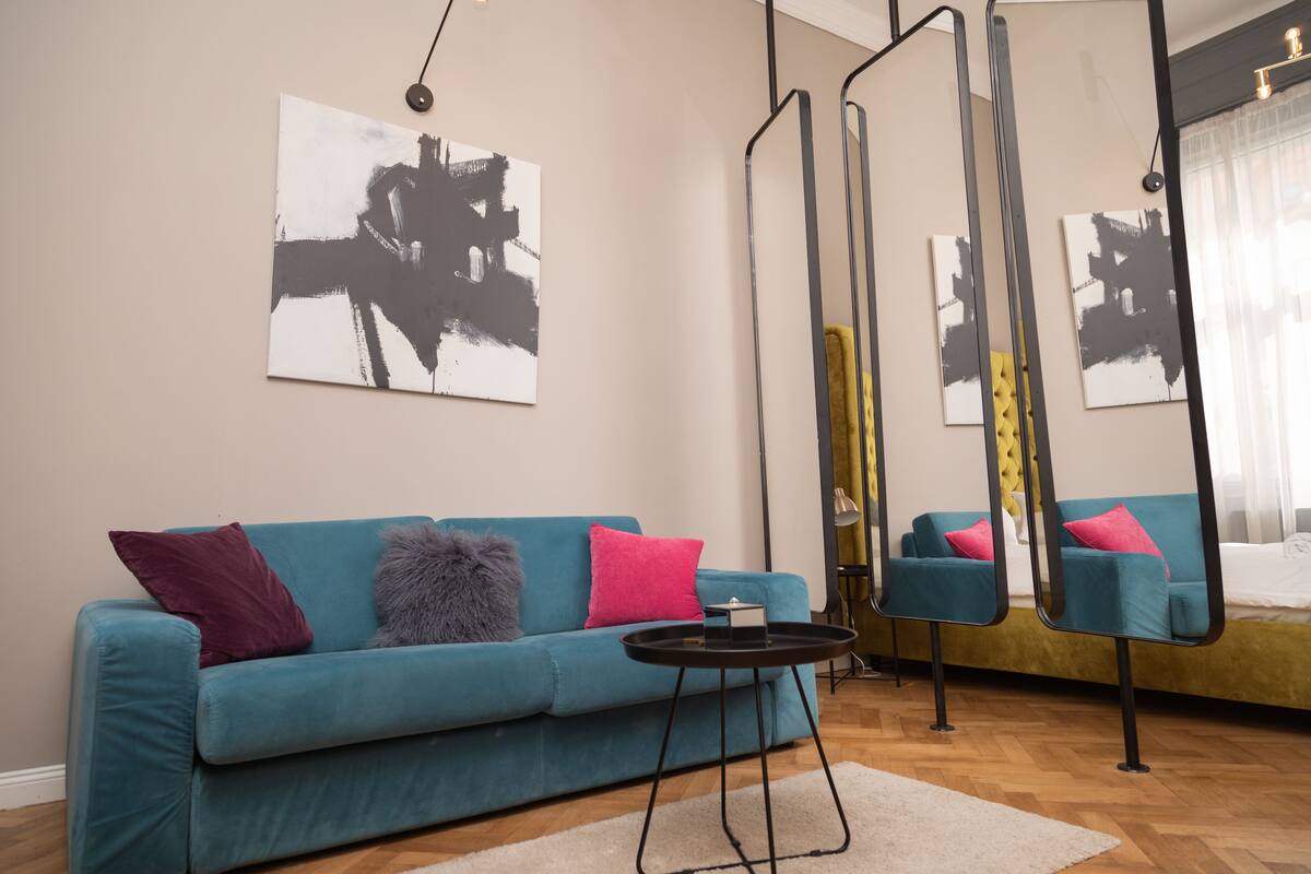 A modern living room with a teal sofa, a small round table, and abstract art on the walls.