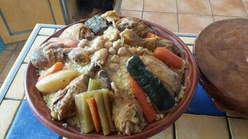 Una olla de barro grande llena de un guiso con carne, verduras y garbanzos.