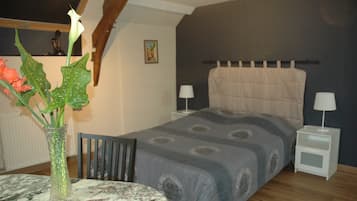 A bedroom with a bed, nightstands, a table with a vase, and a chair.