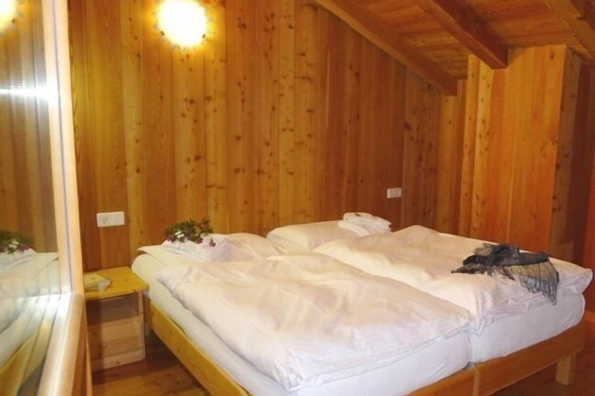 A wooden cabin room with two beds, a small table, and a nightstand.