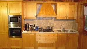 A kitchen with wooden cabinets, a microwave, an oven, a sink, and a stove.