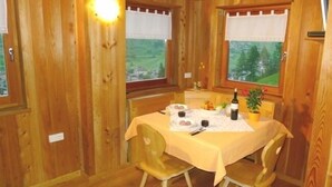 A wooden cabin with a dining table set for two, a bottle of wine, and a small potted plant.