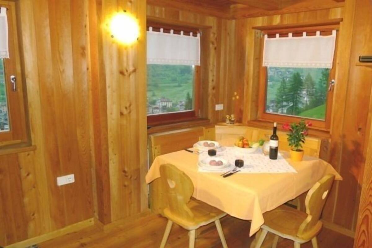 A wooden cabin with a dining table set for two, a bottle of wine, and a small potted plant.