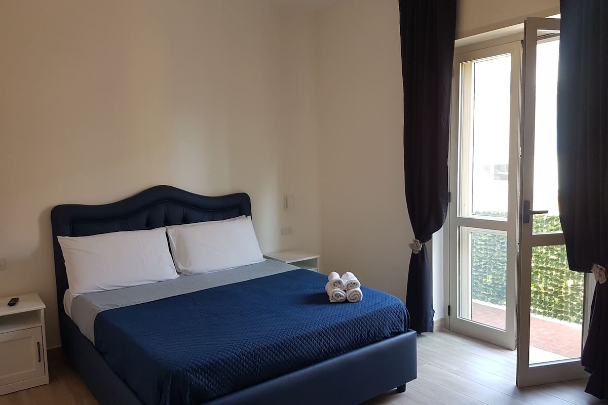Un dormitorio con una cama, una mesita de noche y una ventana con cortinas.