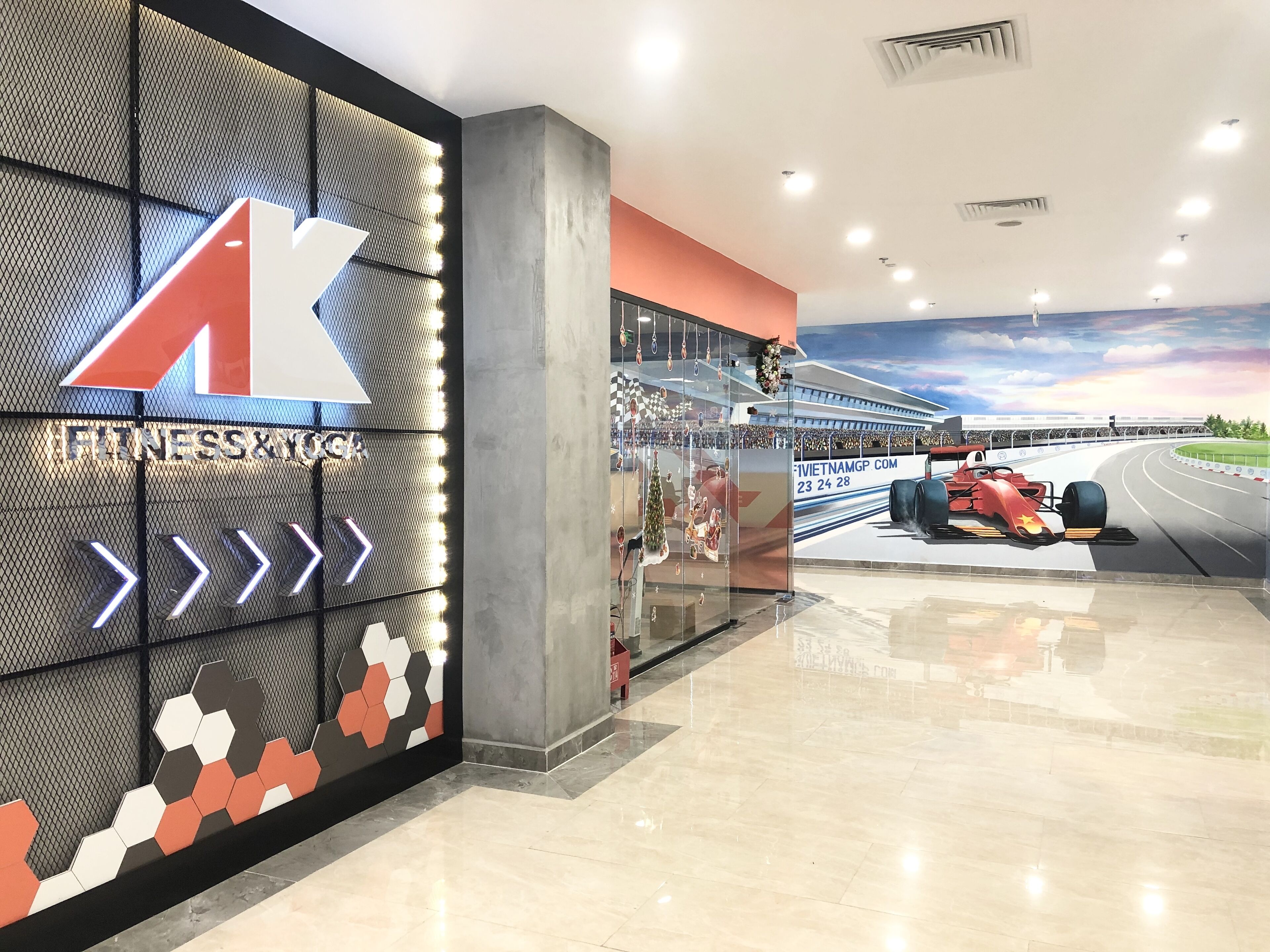 A fitness center with a large illuminated 'A' sign, a race car mural, and a glass storefront.