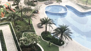 A swimming pool surrounded by greenery, a children's play area, and exercise equipment. - Luxury Condotel Vinhomes Skylake Keangnam (Hanoi)