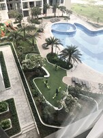 Una piscina rodeada de vegetación, una zona de juegos infantiles y equipo de ejercicio.