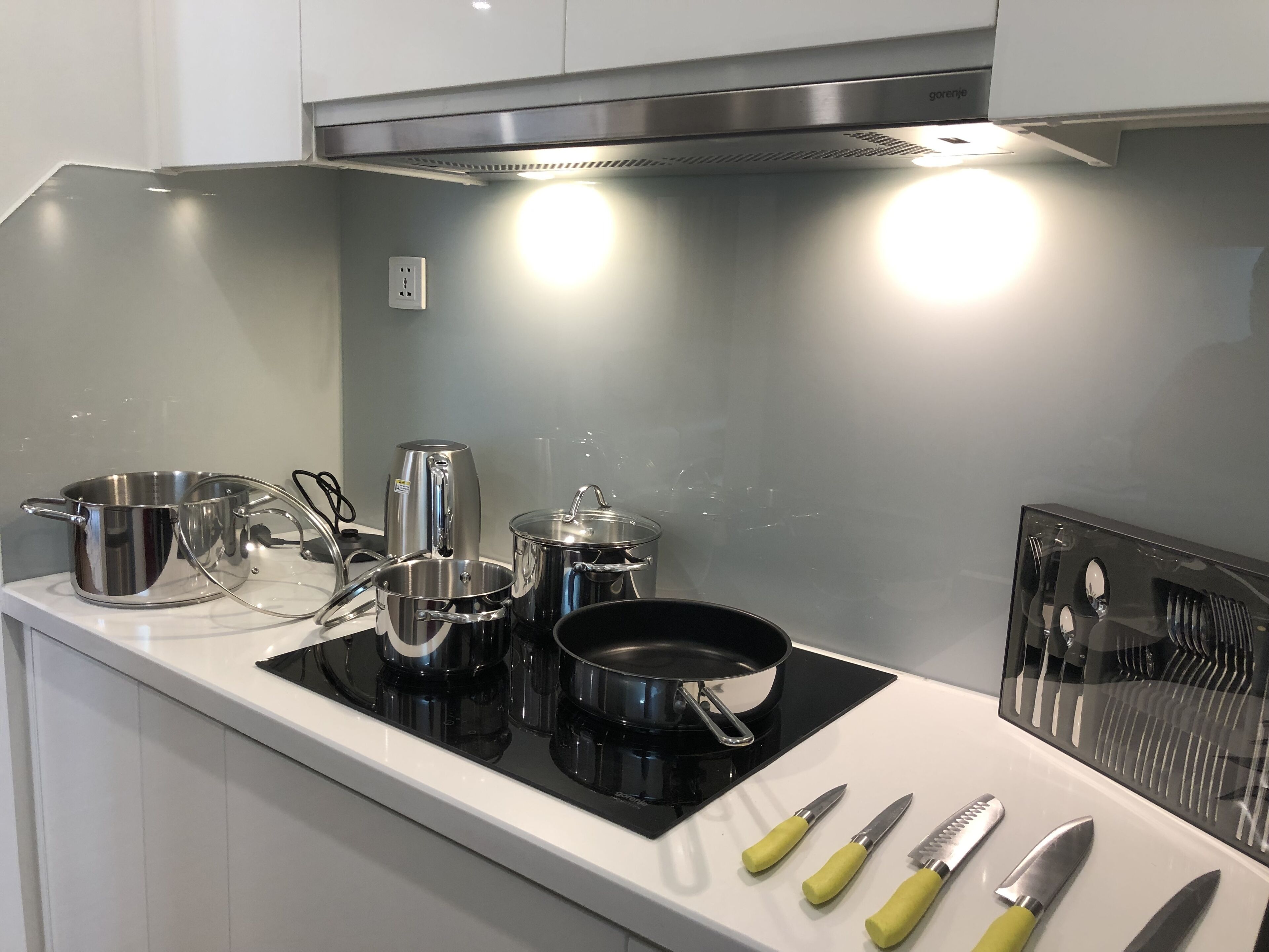 Una cocina moderna con electrodomésticos de acero inoxidable, incluyendo una estufa, ollas y una cafetera.