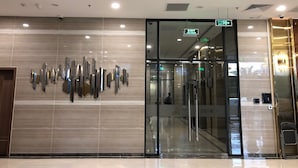 A modern hotel entrance with a glass door, a security camera, and a sign indicating an exit. - Luxury Condotel Vinhomes Skylake Keangnam (Hanoi)