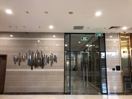 Entrada moderna de hotel con puerta de cristal, cámara de seguridad y señalización de salida.