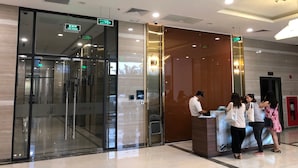 A hotel reception area with a glass entrance, a reception desk, and a digital information screen. - Luxury Condotel Vinhomes Skylake Keangnam (Hanoi)
