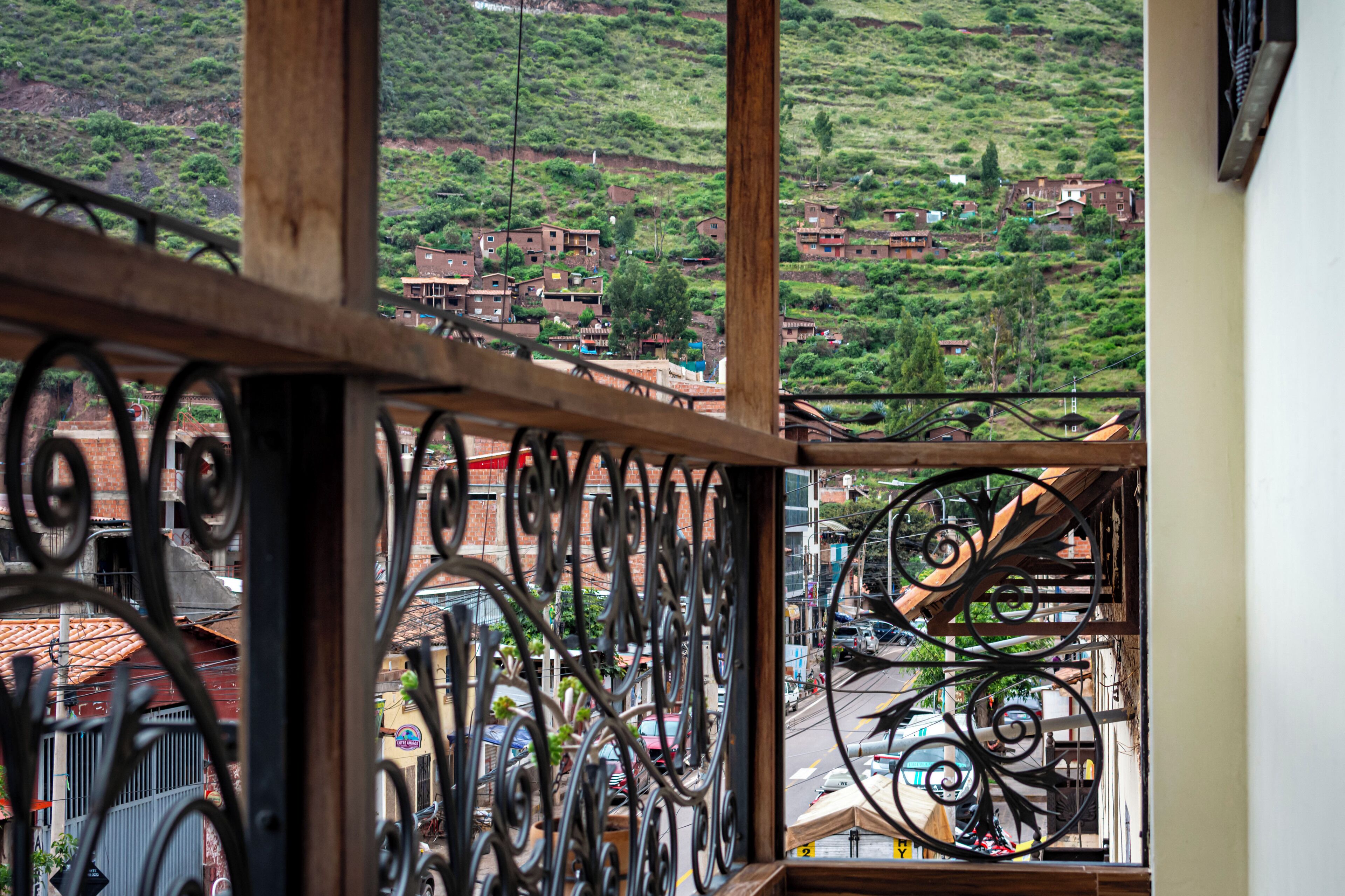 A balcony with wrought iron railings overlooking a hillside with buildings.