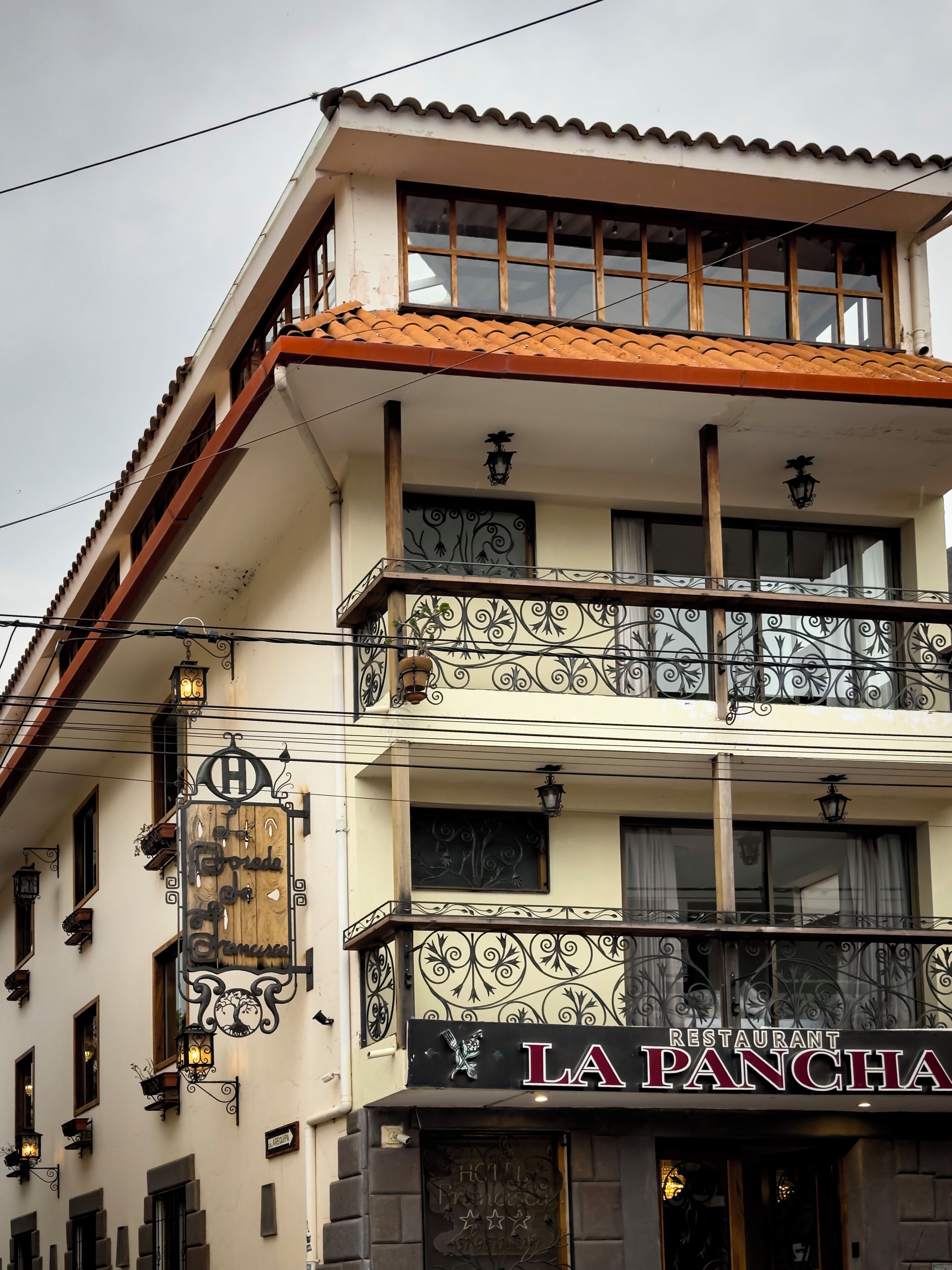 Un edificio de varios pisos con un restaurante llamado 'LA PANCHA' en la planta baja.