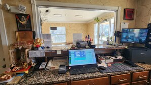 A home office with a desktop computer, a laptop, and a television displaying multiple camera feeds. - Benbrook Inn & Suites (Fort Worth)