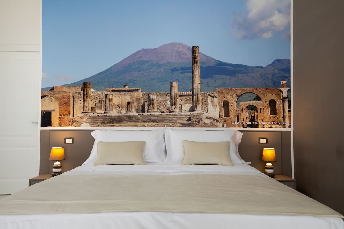 A bed with a view of ancient ruins and a mountain in the background.