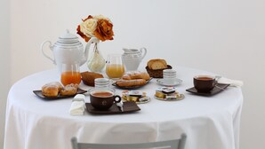 Un desayuno con pasteles, café y jugo sobre una mesa.