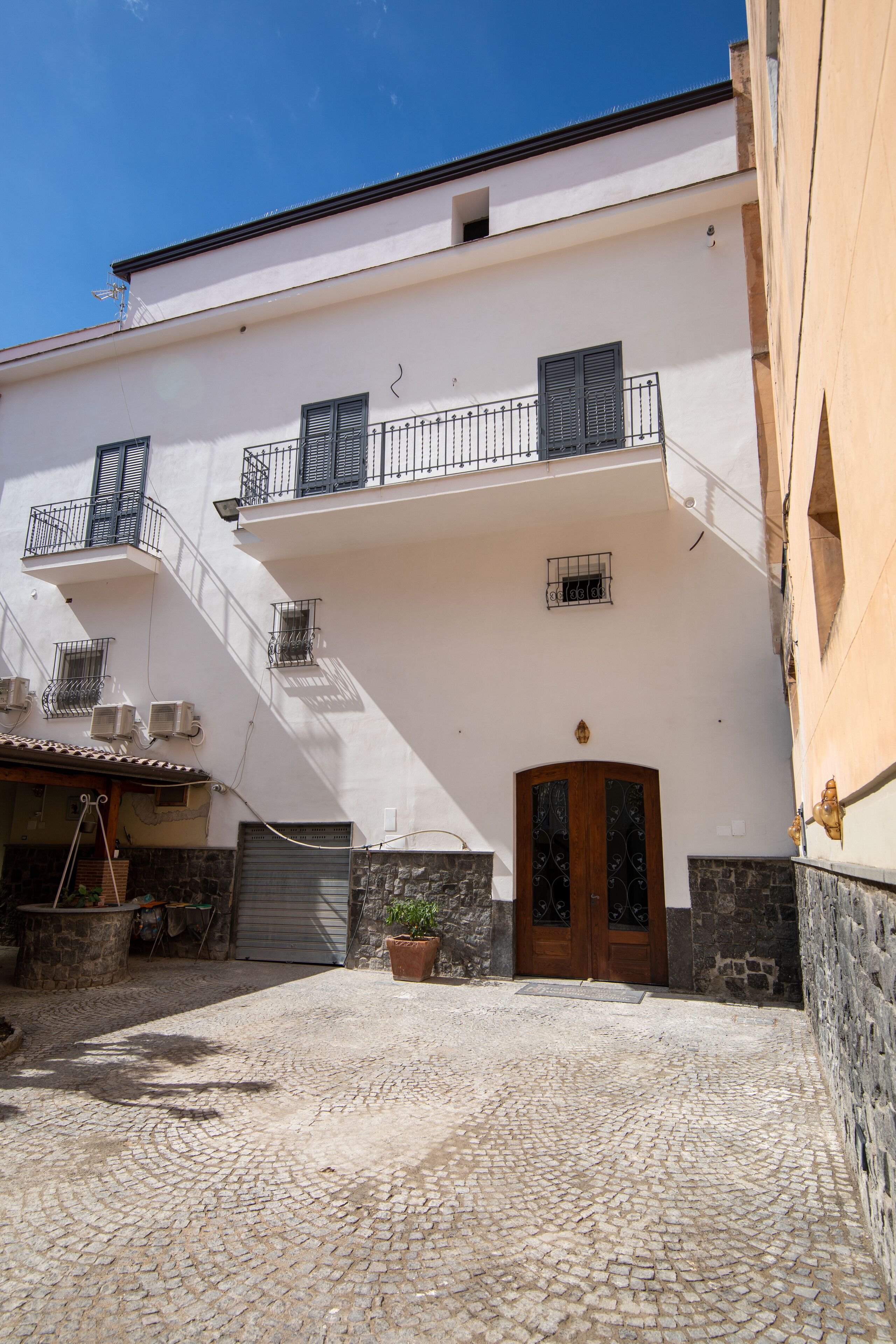 Ein Gebäude mit weißer Fassade, einer Holztür und einem Balkon mit Metallgeländern.