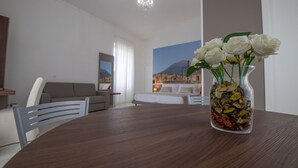 Una sala moderna con una mesa de comedor, un jarrón con flores y vistas a la montaña a través de una ventana.
