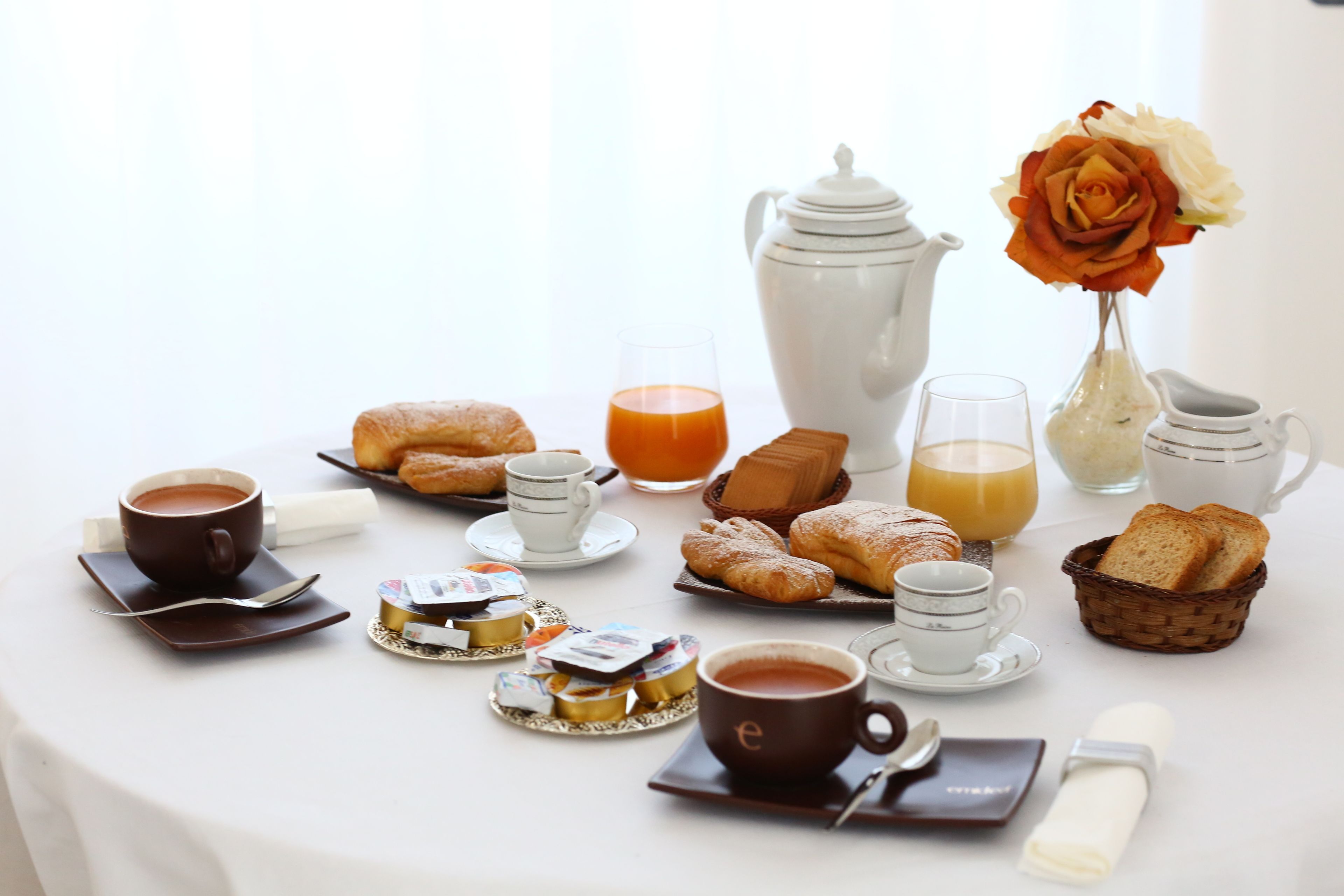 A breakfast setting with pastries, coffee, and juice on a table.