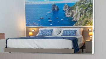 A bedroom with a bed, two bedside lamps, and a large painting of a coastal scene.