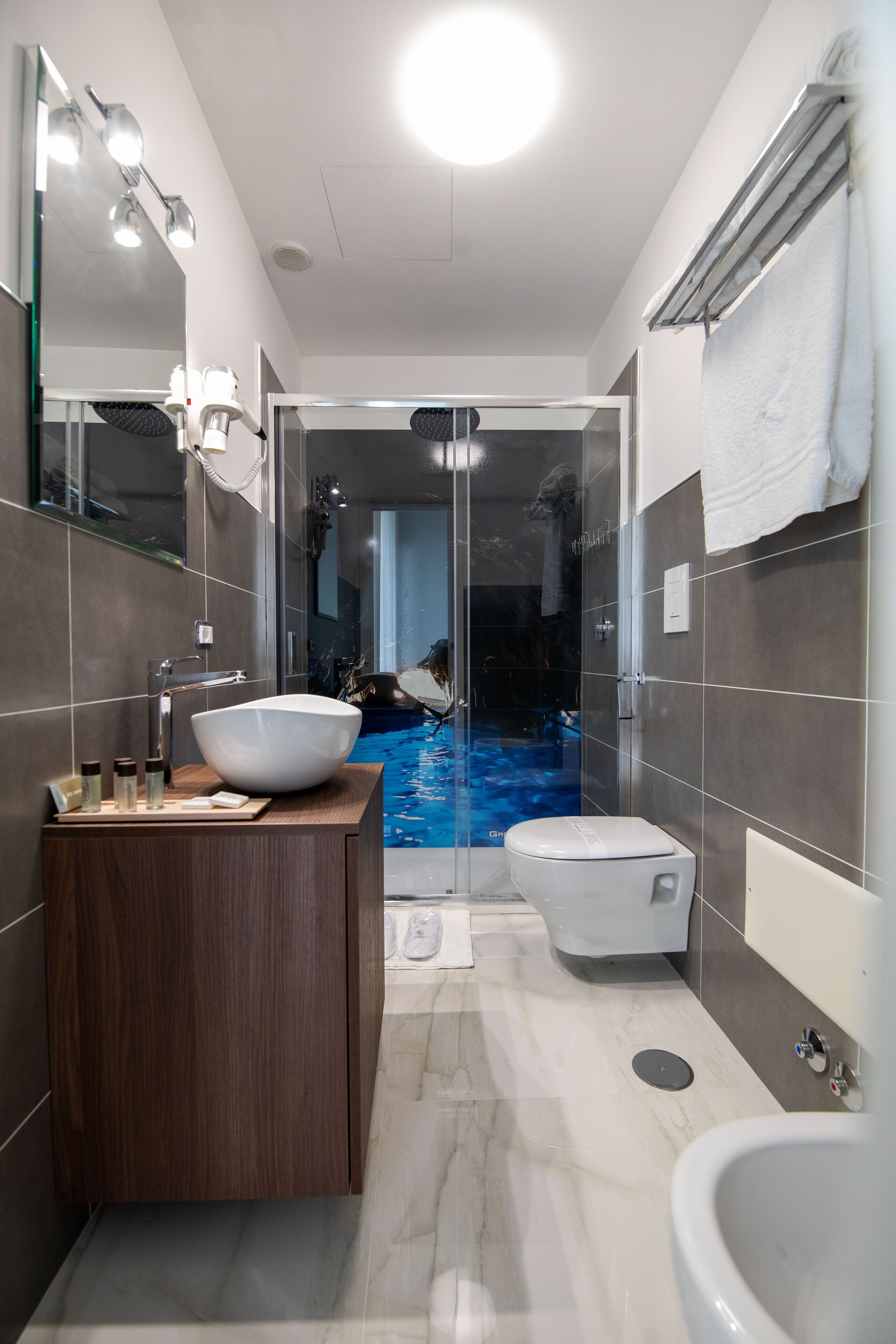 Ein modernes Badezimmer mit einem großen, weißen Waschbecken, einer Toilette und einer gläsernen Dusche.